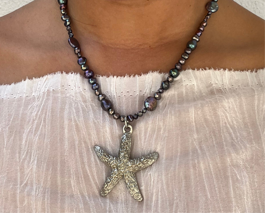 Shop Querida 17 inch long necklace inspired by night walks by the beach stargazing and appreciation of nature made with freshwater pearls that have dark purple, green, black hues, vintage second hand sourced stainless steel starfish Beachy mystical bohemian fairy 