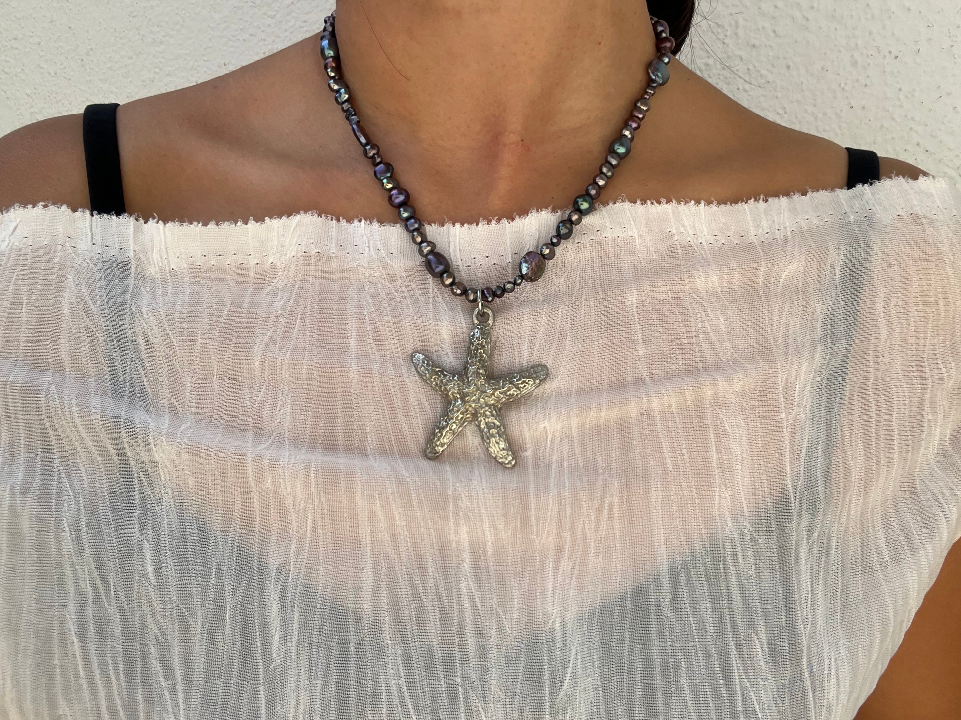Shop Querida 17 inch long necklace inspired by night walks by the beach stargazing and appreciation of nature made with freshwater pearls that have dark purple, green, black hues, vintage second hand sourced stainless steel starfish Beachy mystical bohemian fairy 